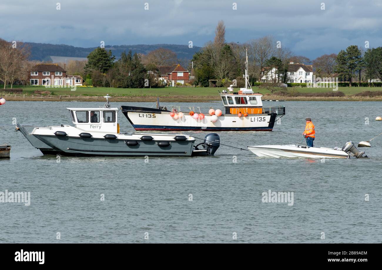 Traghetto che traina una barca rotta nel porto di Chichester vicino a Itchenor, West Sussex, Regno Unito Foto Stock