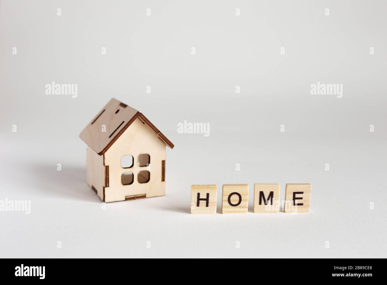 Modello di casa in legno e lettere in legno con l'iscrizione Home. Sfondo bianco. Spazio di copia Foto Stock