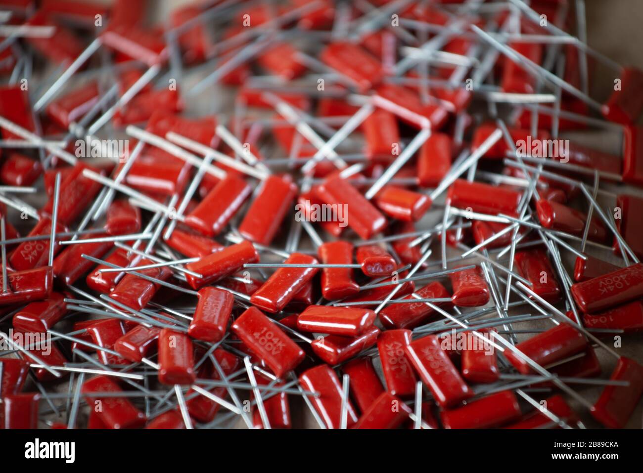 Il primo piano di un gruppo di condensatori rossi si trova l'uno sopra l'altro in una fabbrica di computer e apparecchiature per ufficio. Concetto di parti di qualità. Lotto all'ingrosso Foto Stock