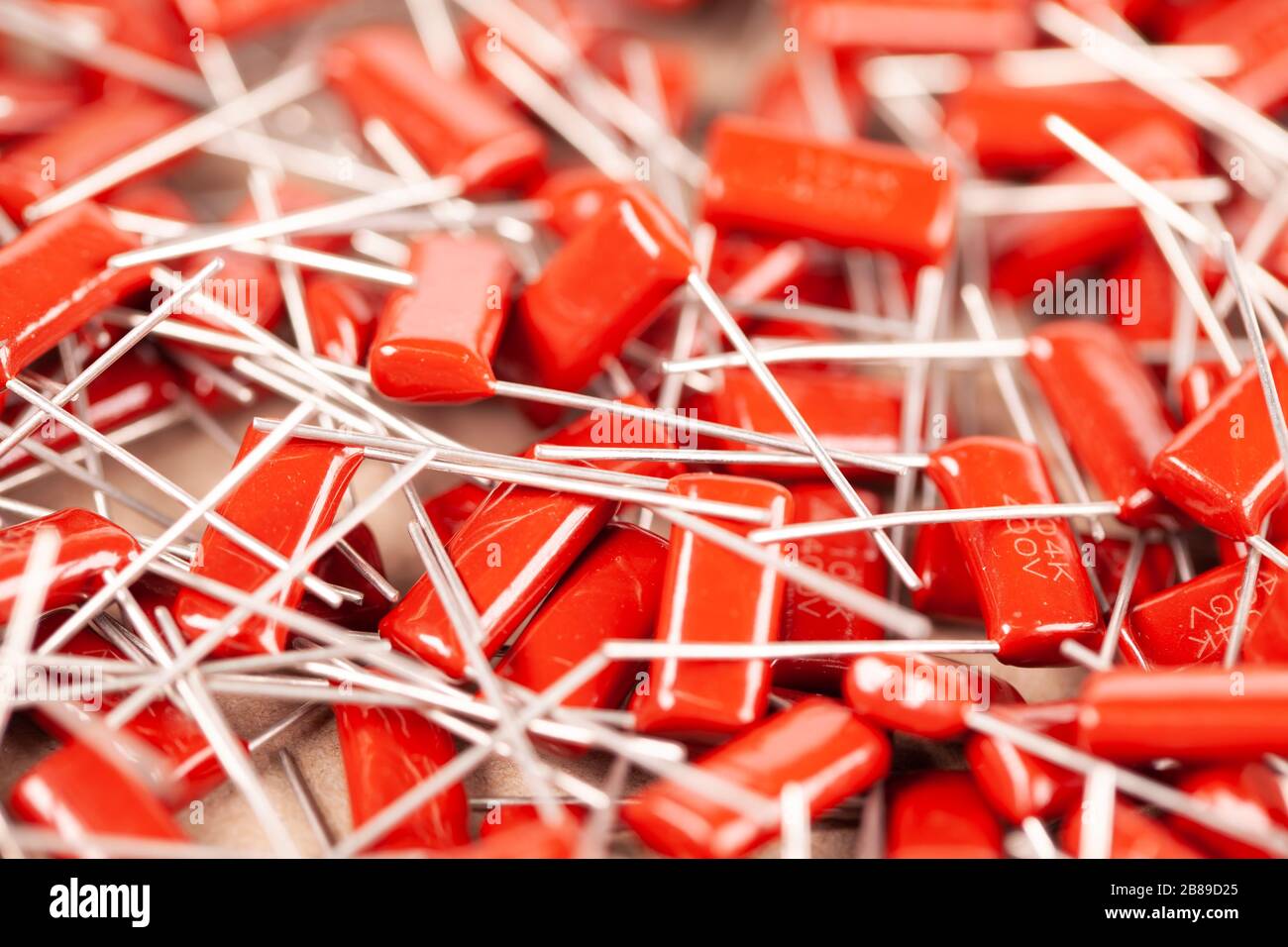 Il primo piano di un gruppo di condensatori rossi si trova l'uno sopra l'altro in una fabbrica di computer e apparecchiature per ufficio. Concetto di parti di qualità. Lotto all'ingrosso Foto Stock