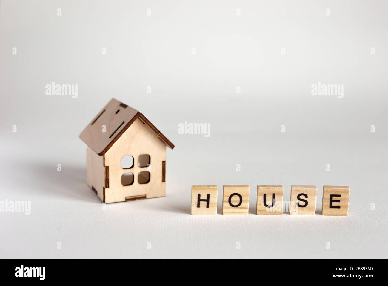 Modello di casa in legno e lettere in legno con l'iscrizione Casa. Sfondo bianco. Spazio di copia Foto Stock