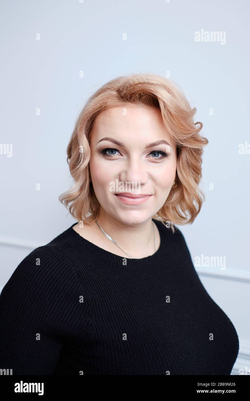 donna incinta in abito nero sorridente toccando pancia Foto Stock