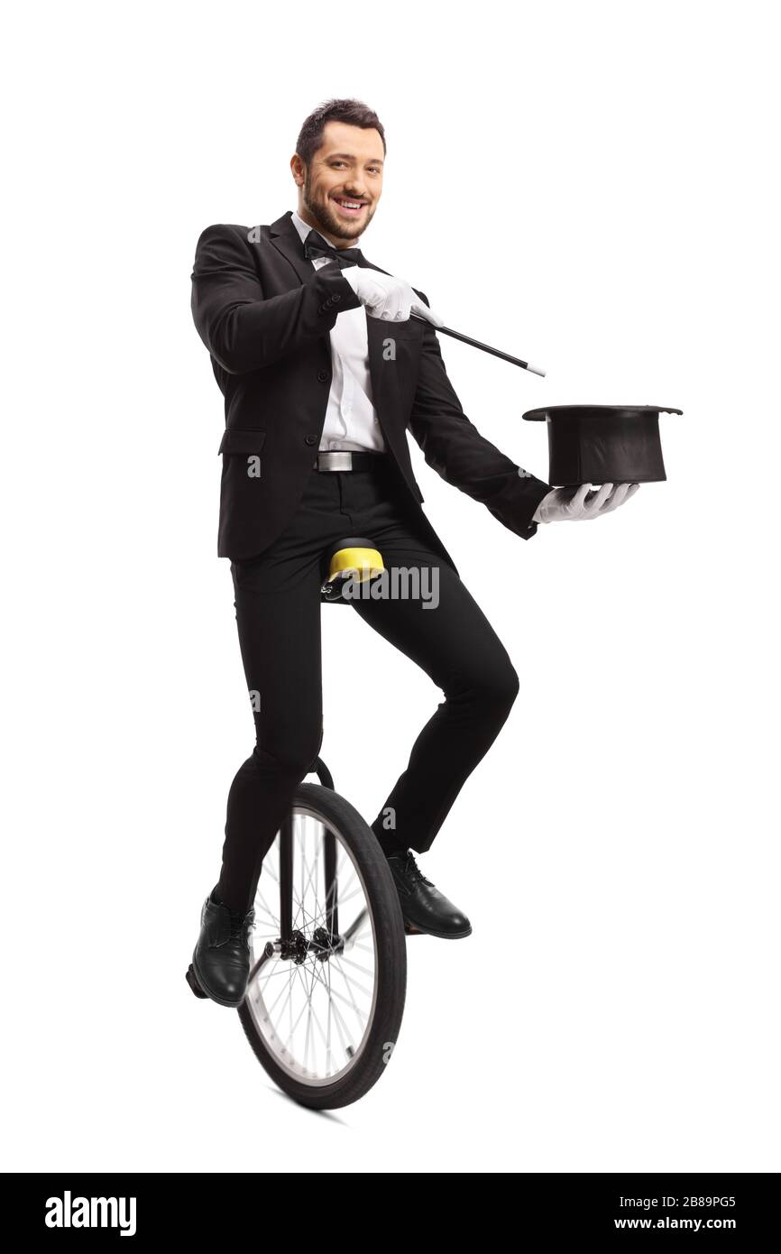 Ritratto a tutta lunghezza di un mago su un monociclo che esegue un trucco cappello isolato su sfondo bianco Foto Stock