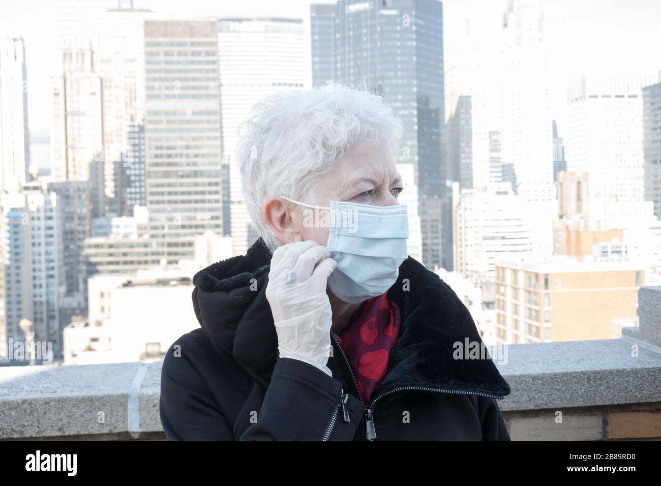 La donna anziana con problemi di salute e sicurezza indossa una maschera protettiva per il viso a Midtown Manhattan, New York City, USA Foto Stock