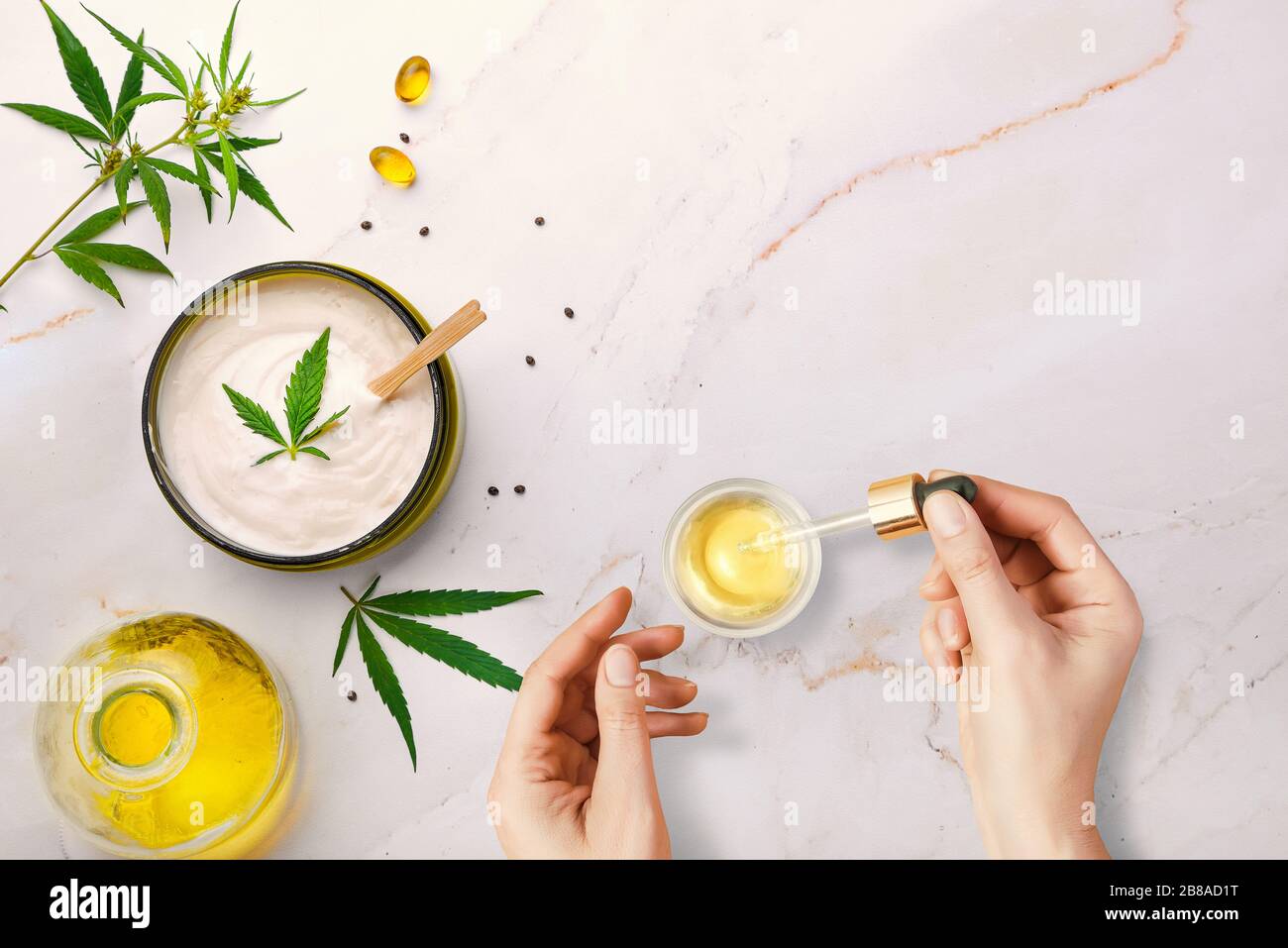 Pipetta con olio cosmetico CBD in mano femminile su sfondo tavolo con cosmetici con cannabis e foglie di marijuana Foto Stock Pipetta con olio cosmetico CBD in mano femminile su sfondo tavolo con cosmetici con cannabis e foglie di marijuana Foto Stock
