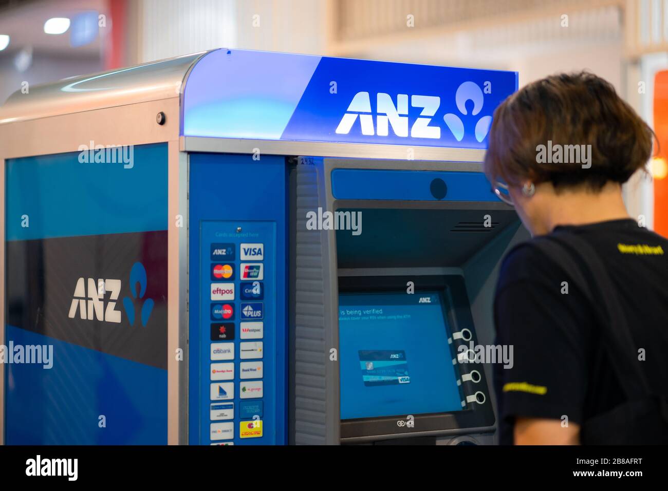 Primo piano ANZ atm Autotic Teller Machine, la grande Banca di Sydney, con un uomo disfocused prelievo di denaro, Australia: 19-03-2020 Foto Stock