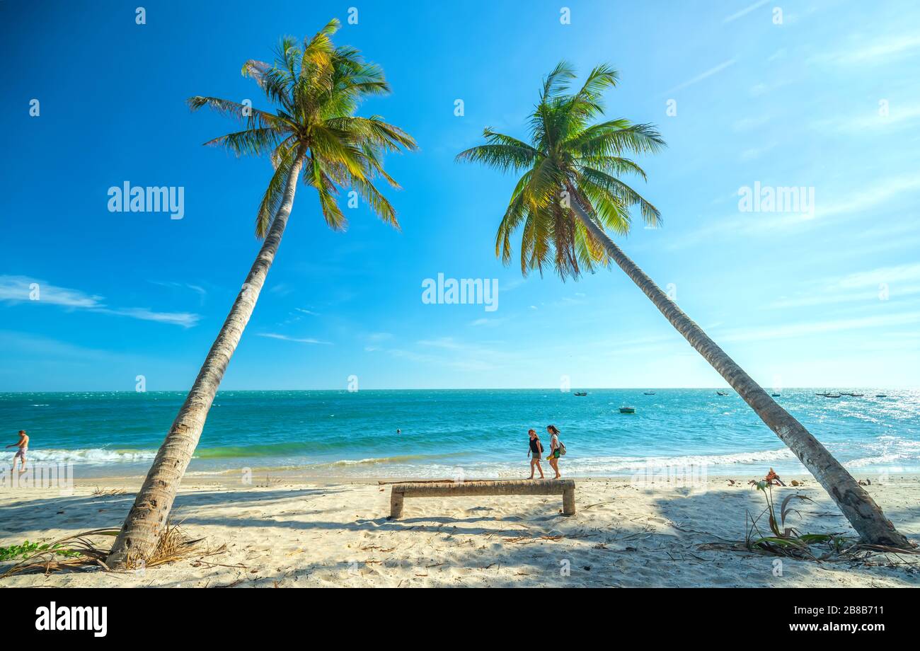 Un paio di turisti stranieri stanno facendo una piacevole passeggiata in una splendida baia nel pomeriggio estivo su una spiaggia tropicale a Mui NE, Vietnam Foto Stock