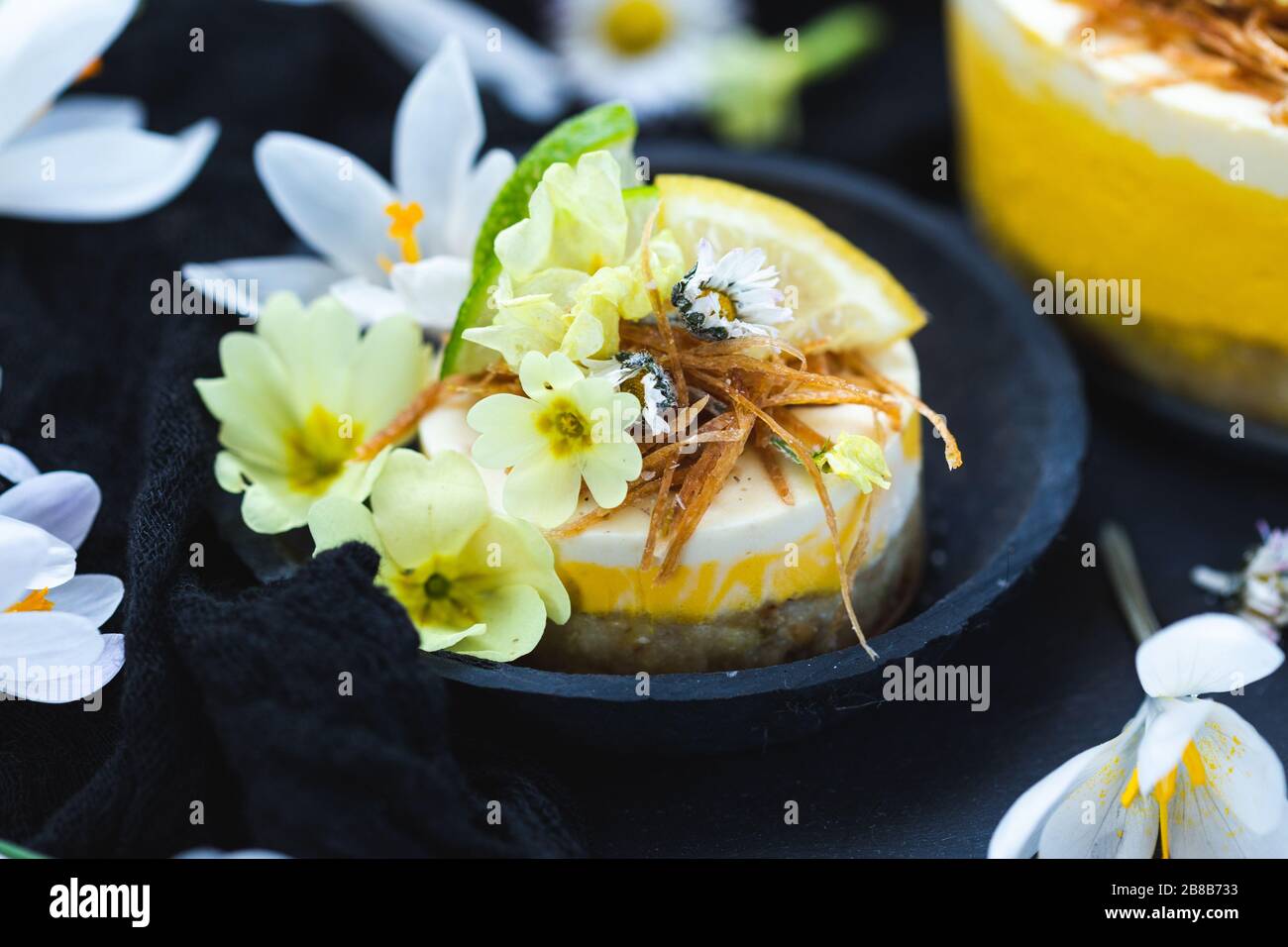 Primo piano di una piccola torta vegana cruda con lime e limone in una ciotola nera Foto Stock
