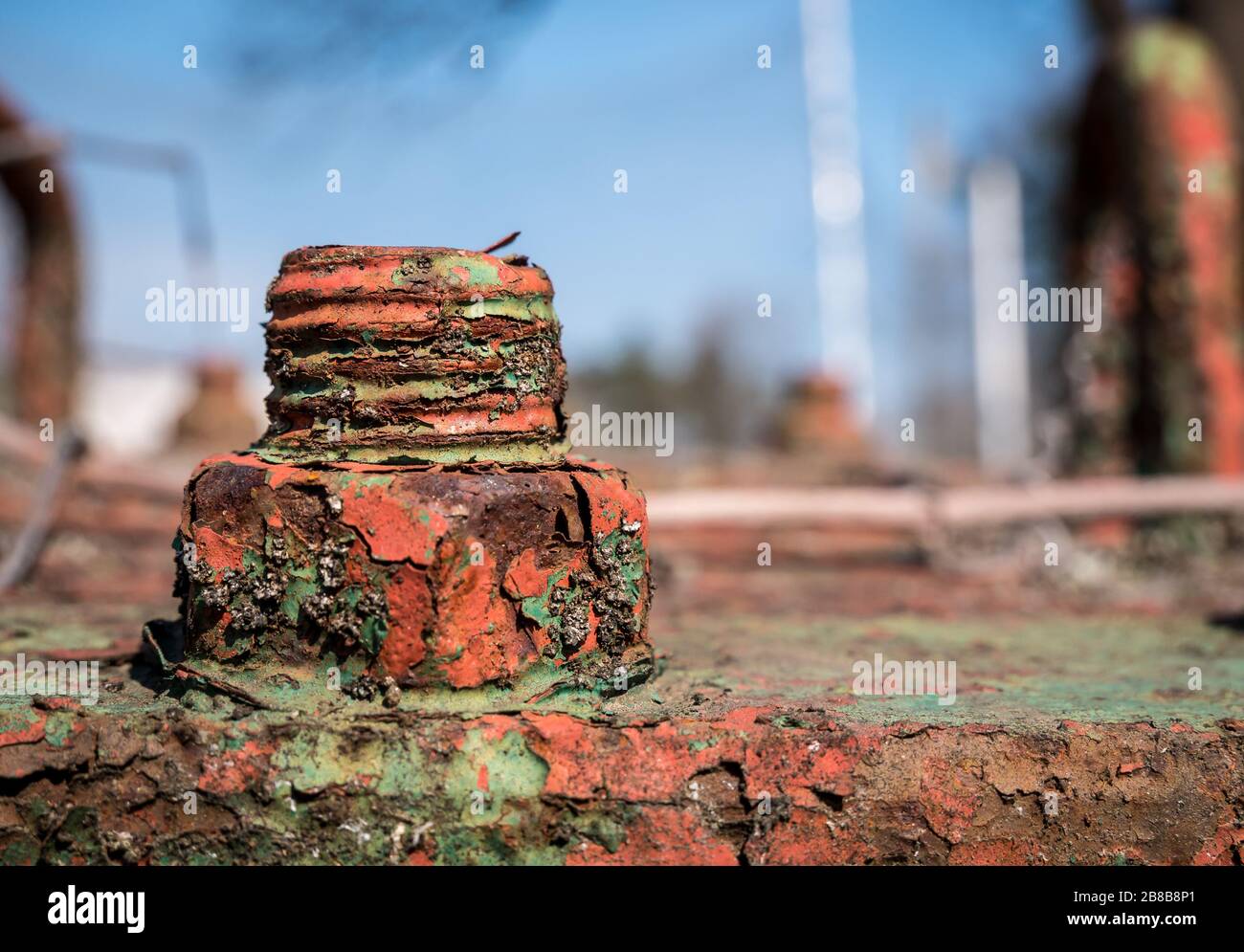 Bullone arrugginito con sfondo sfocato e vernice verde. Foto Stock