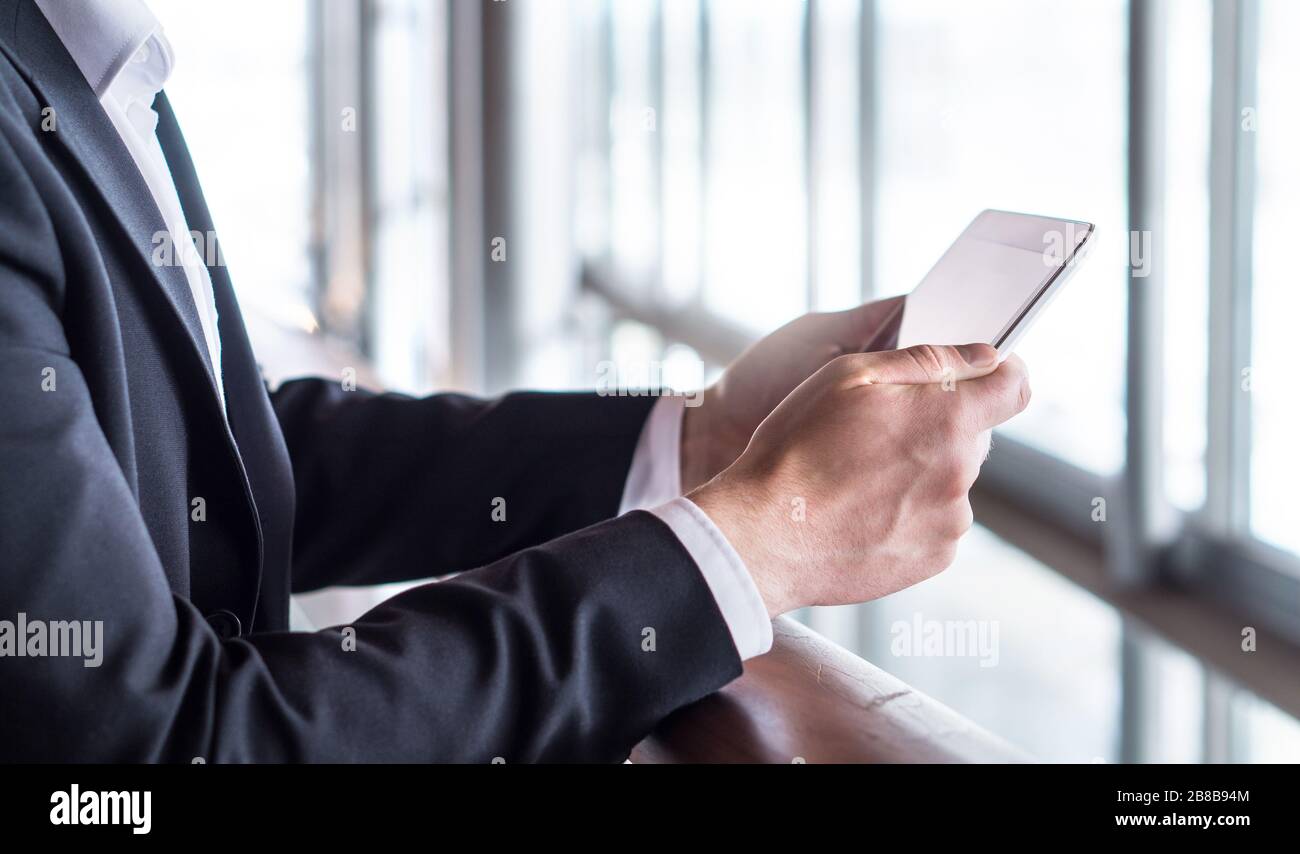Uomo d'affari che usa un tablet o che legge notizie con un tablet. Uomo d'affari che lavora in un moderno edificio d'ufficio con un dispositivo mobile intelligente. Foto Stock