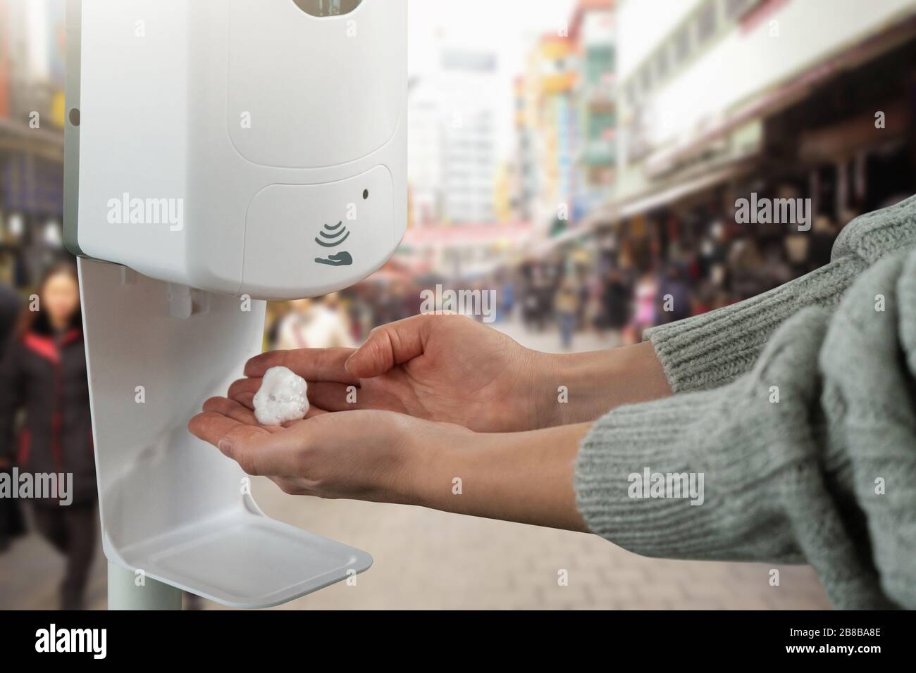 Donna tratta le mani con un disinfettante in un negozio di alimenti durante l'epidemia di coronavirus Foto Stock