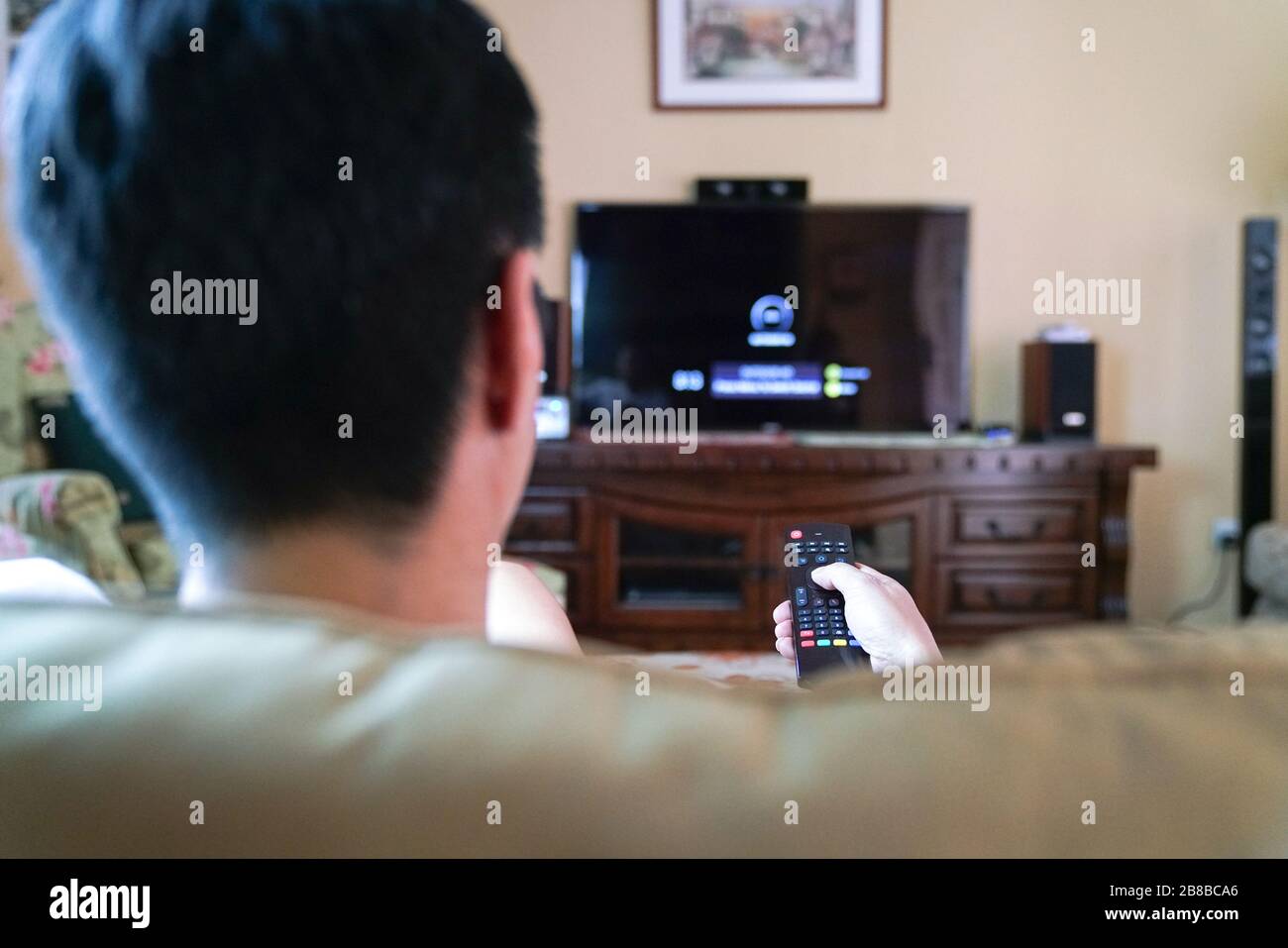 Uomo che guarda la tv con attenzione sulle mani sul telecomando. Home entertainment o concetto di soggiorno a casa. Foto Stock