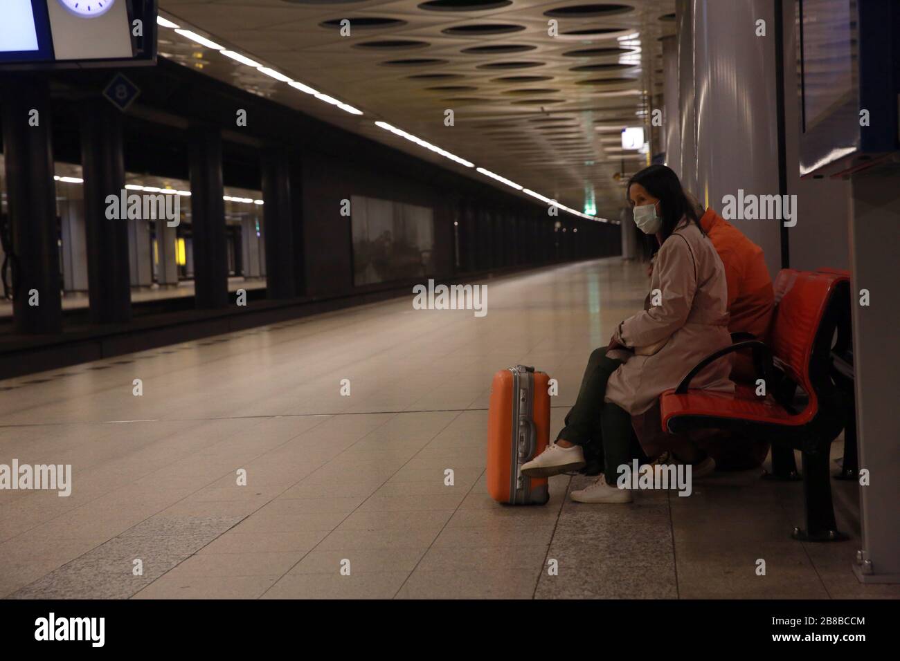 AMSTERDAM, PAESI BASSI - 11 MARZO 2020: La donna asiatica viaggia indossando la protezione del viso per prevenire il coronavirus, nella stazione ferroviaria dell'aeroporto. Foto Stock