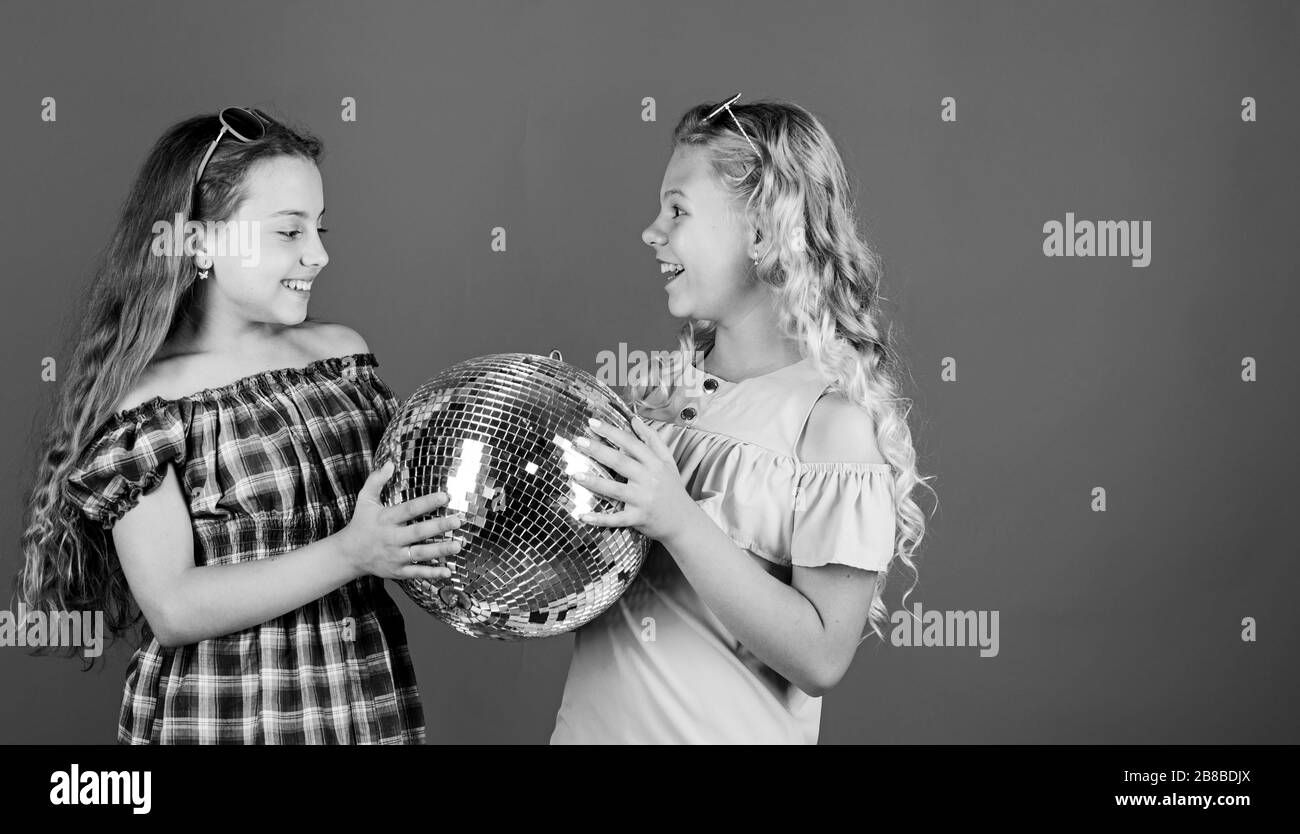 Iniziare a parte. Allegro kids tenere palla da discoteca. Discoteca danze. Musica retrò. Gli specchi riflettenti discoteca luci di atmosfera. Holiday celebrazione. Concetto di intrattenimento. Sorelle amici con palla da discoteca. Foto Stock
