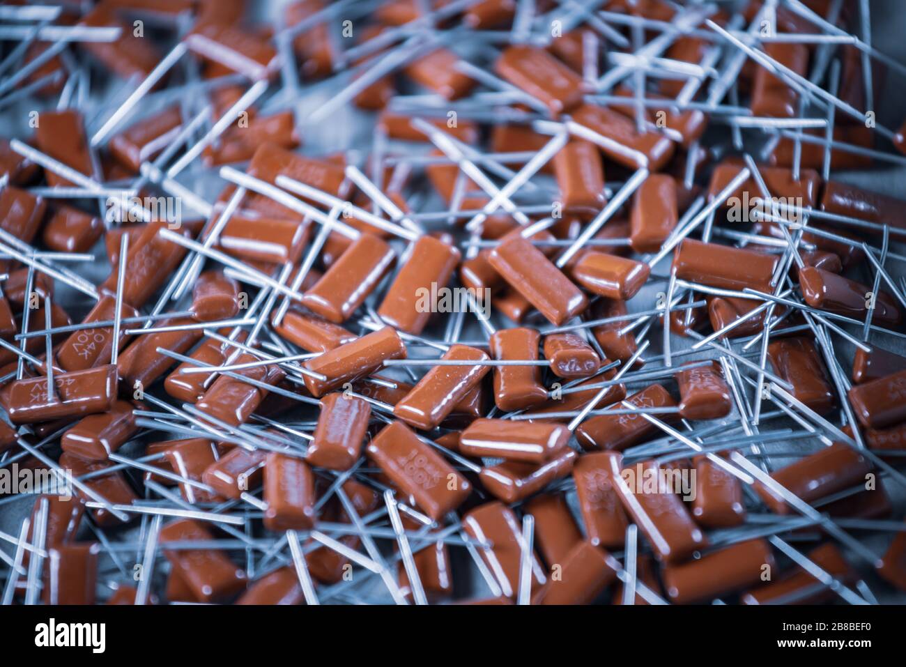 Il primo piano di un gruppo di condensatori rossi si trova l'uno sopra l'altro in una fabbrica di computer e apparecchiature per ufficio. Concetto di parti di qualità. Lotto all'ingrosso Foto Stock