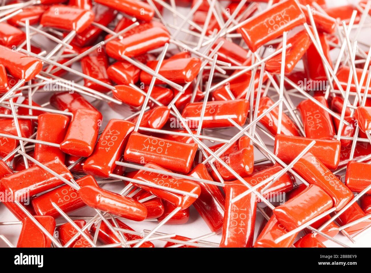 Il primo piano di un gruppo di condensatori rossi si trova l'uno sopra l'altro in una fabbrica di computer e apparecchiature per ufficio. Concetto di parti di qualità. Lotto all'ingrosso Foto Stock