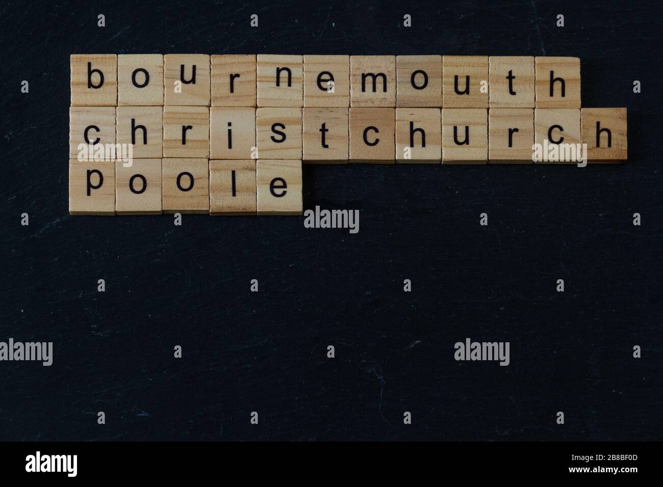 Bournemouth Christchurch Poole scritto in blocchi di lettere di legno su sfondo scuro ardesia. CopySpace, paesaggio Foto Stock