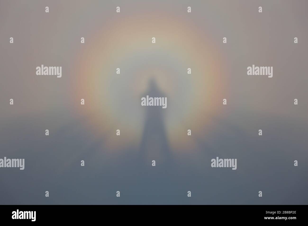 La silhouette avvolta dall'arcobaleno di un corpo umano si riflette nella nebbia Foto Stock