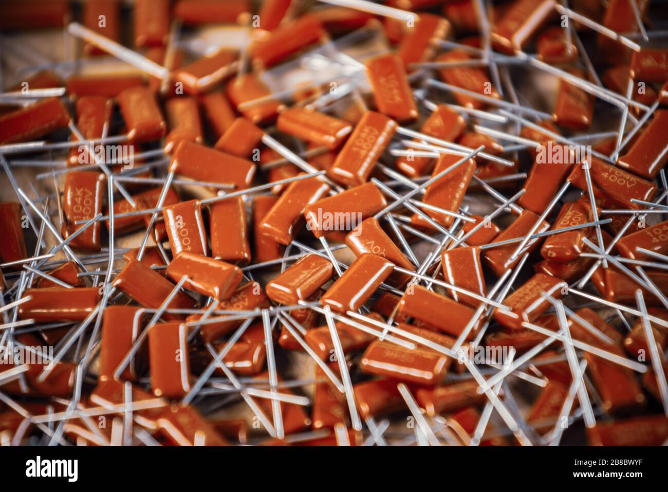 Il primo piano di un gruppo di condensatori rossi si trova l'uno sopra l'altro in una fabbrica di computer e apparecchiature per ufficio. Concetto di parti di qualità. Lotto all'ingrosso Foto Stock