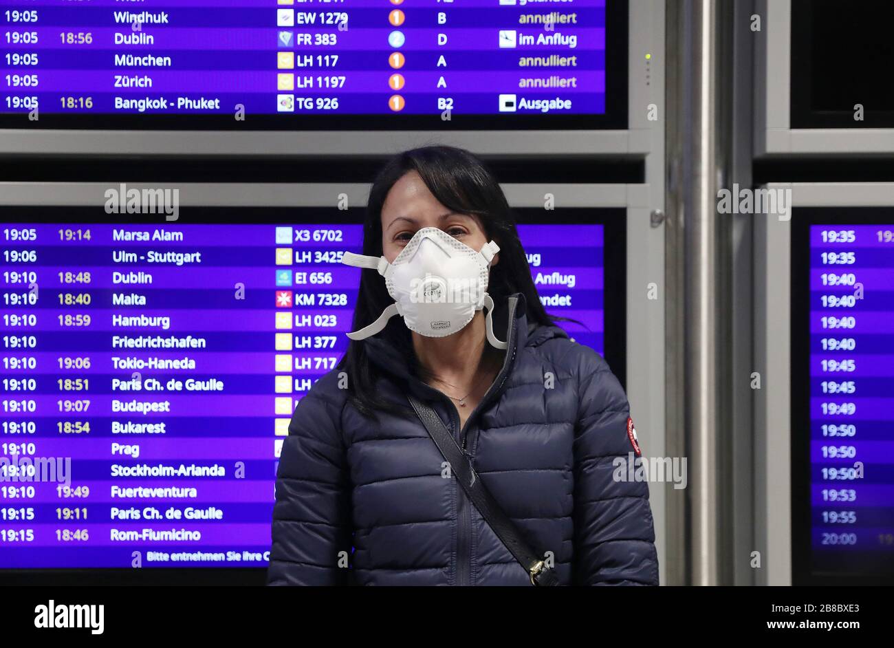 Francoforte, Germania. 2020 marzo 20.03.2020. Primo: Generale, Corona Virus, Covid-19, Crisis, Aeroporto di Coronavirus, Aeroporto Frankfurt Gate B 2, Terminal degli arrivi C Display board con gli orari di arrivo dell'aeromobile in arrivo, UNA donna con maschera protettiva, maschera, bocca e protezione del naso è in attesa di fronte all'imbarco degli arrivi, Tabellone con gli orari di arrivo degli aerei, | utilizzo nel mondo Credit: dpa/Alamy Live News Foto Stock