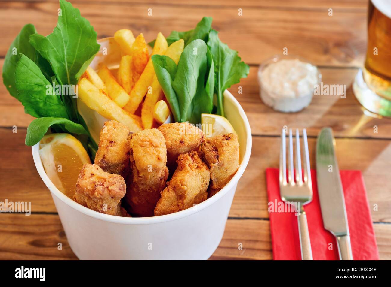 Secchio di dita di pesce con salsa e birra su tavola di legno Foto Stock