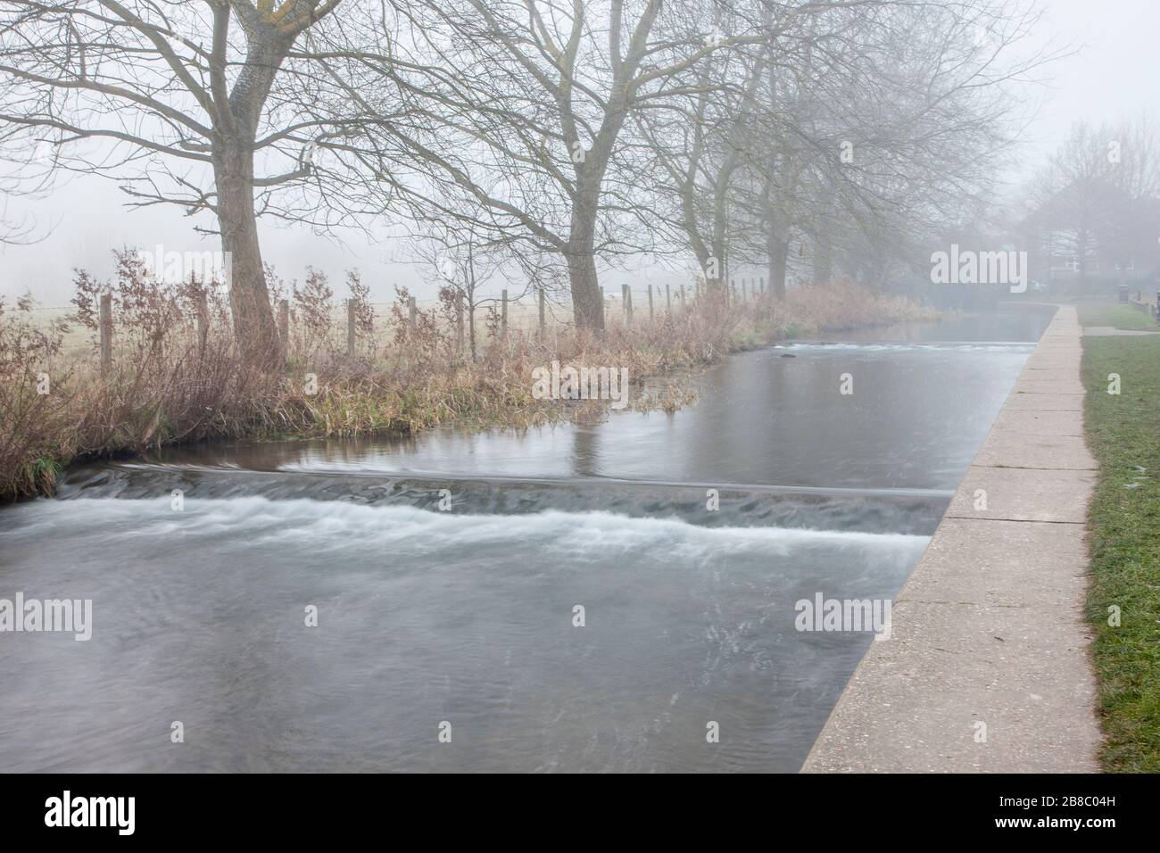 fiume che scorre in una giornata nebbiosa e nebbia Foto Stock