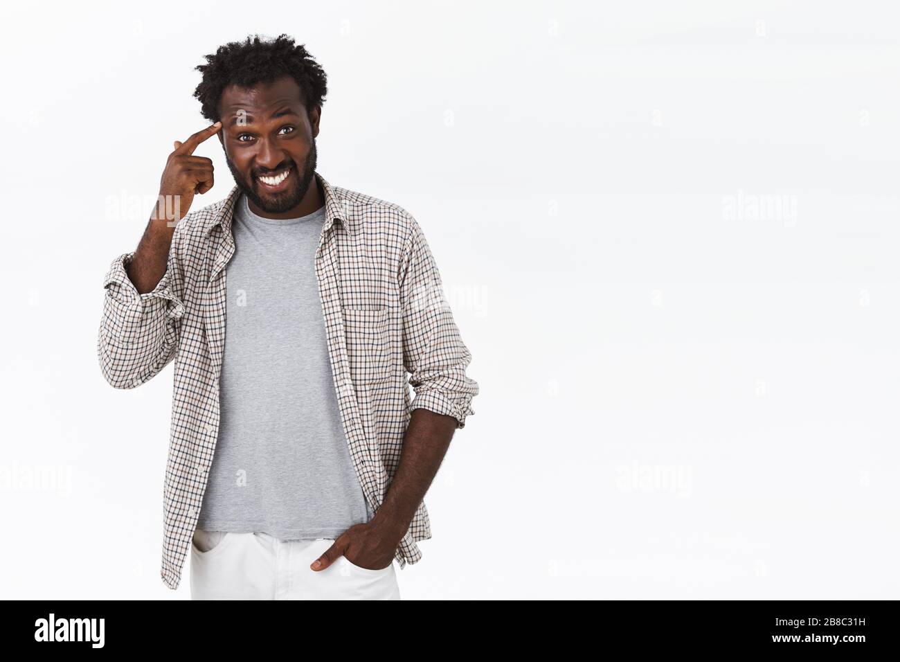 Pensateci. Tipo insistono che dovreste fare le scelte saggiamente. Attraente sorridente, felice uomo afro-americano che grinning, indicando il tempio o il cervello e. Foto Stock