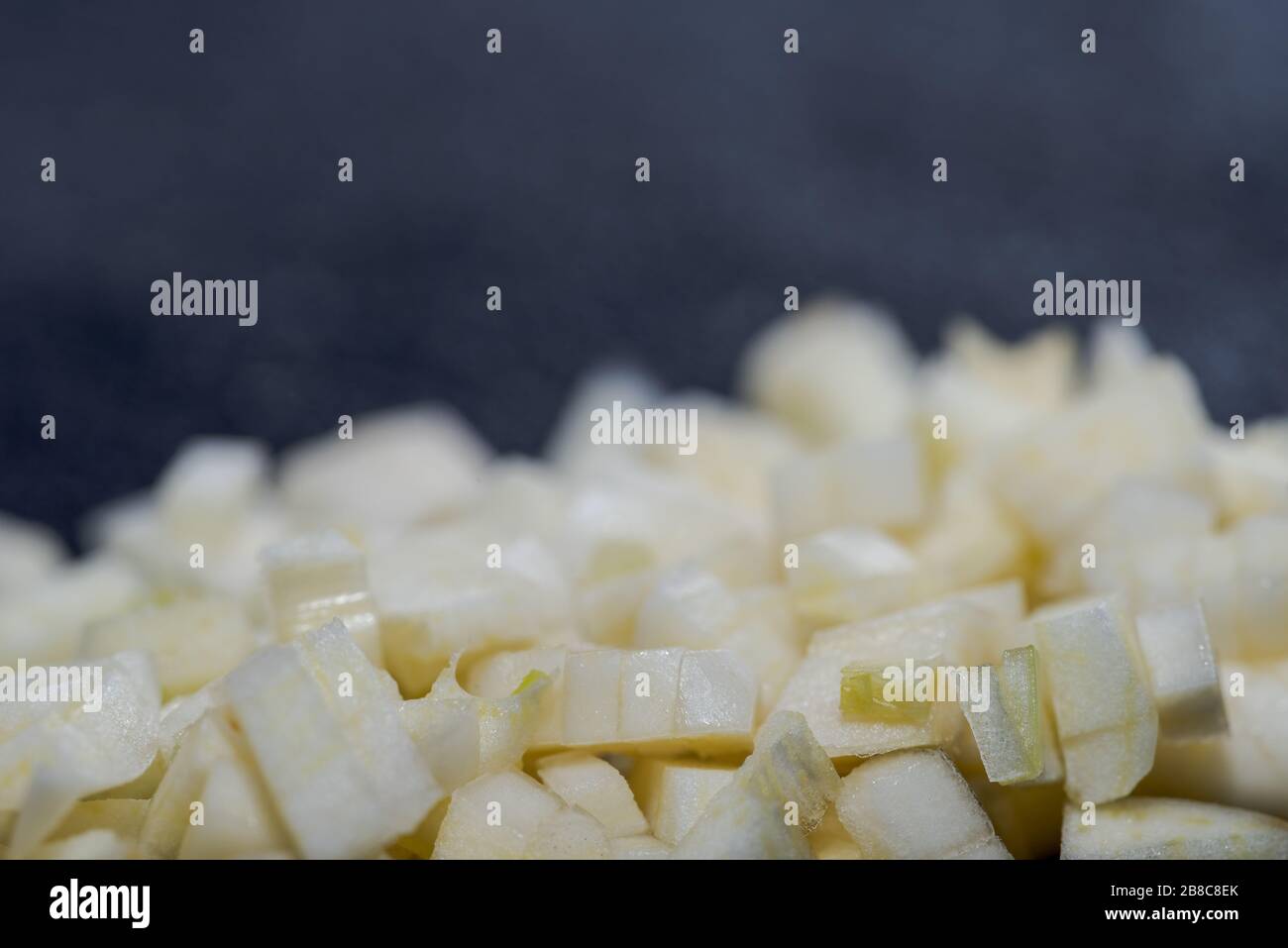 Particolare di aglio piccolo tagliato adagiato su tavola nera da cucina con sfondo sfocato Foto Stock