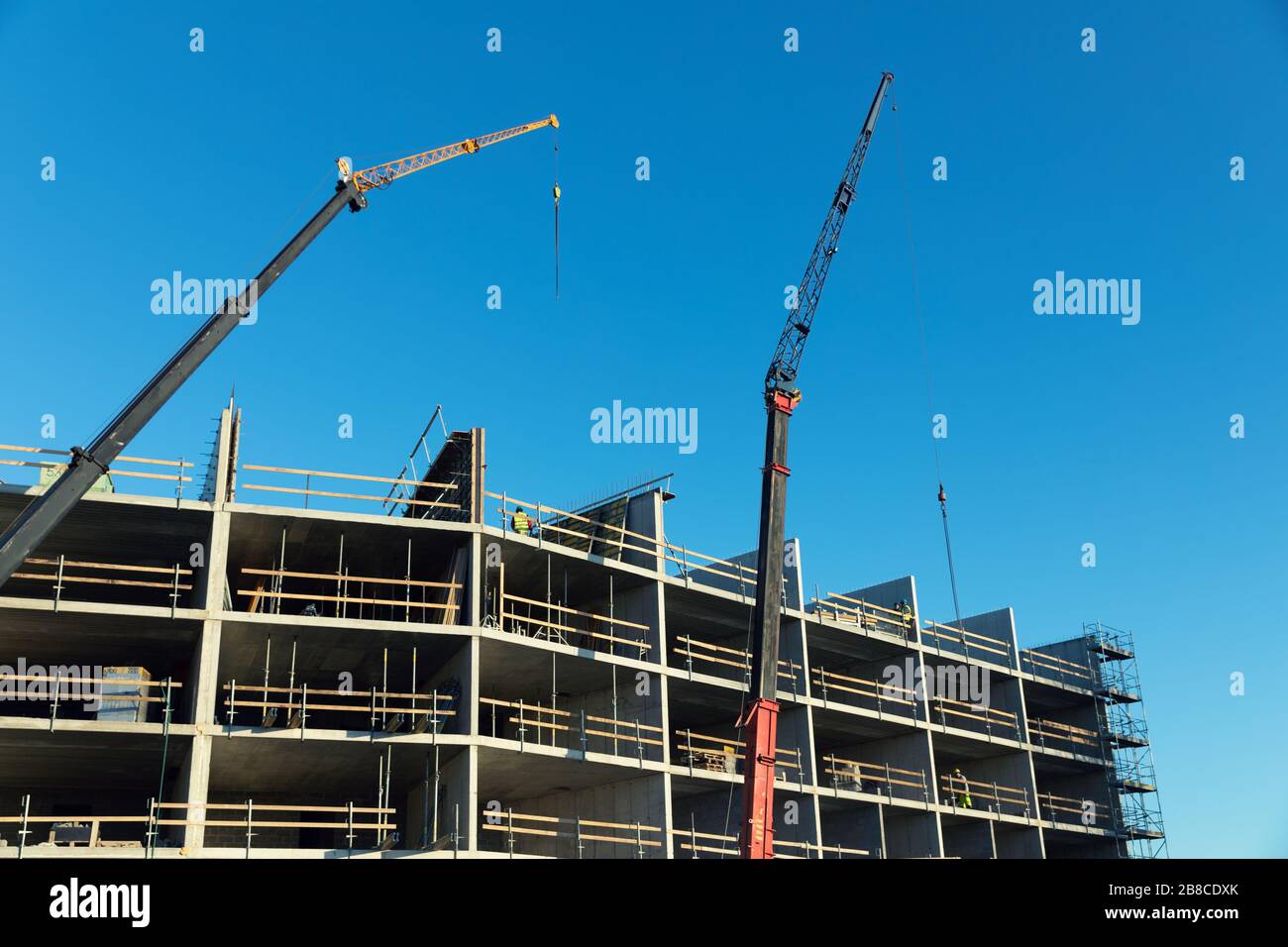 sviluppo di alloggi - lavoratori e gru che lavorano sul cantiere di costruzione di appartamenti Foto Stock