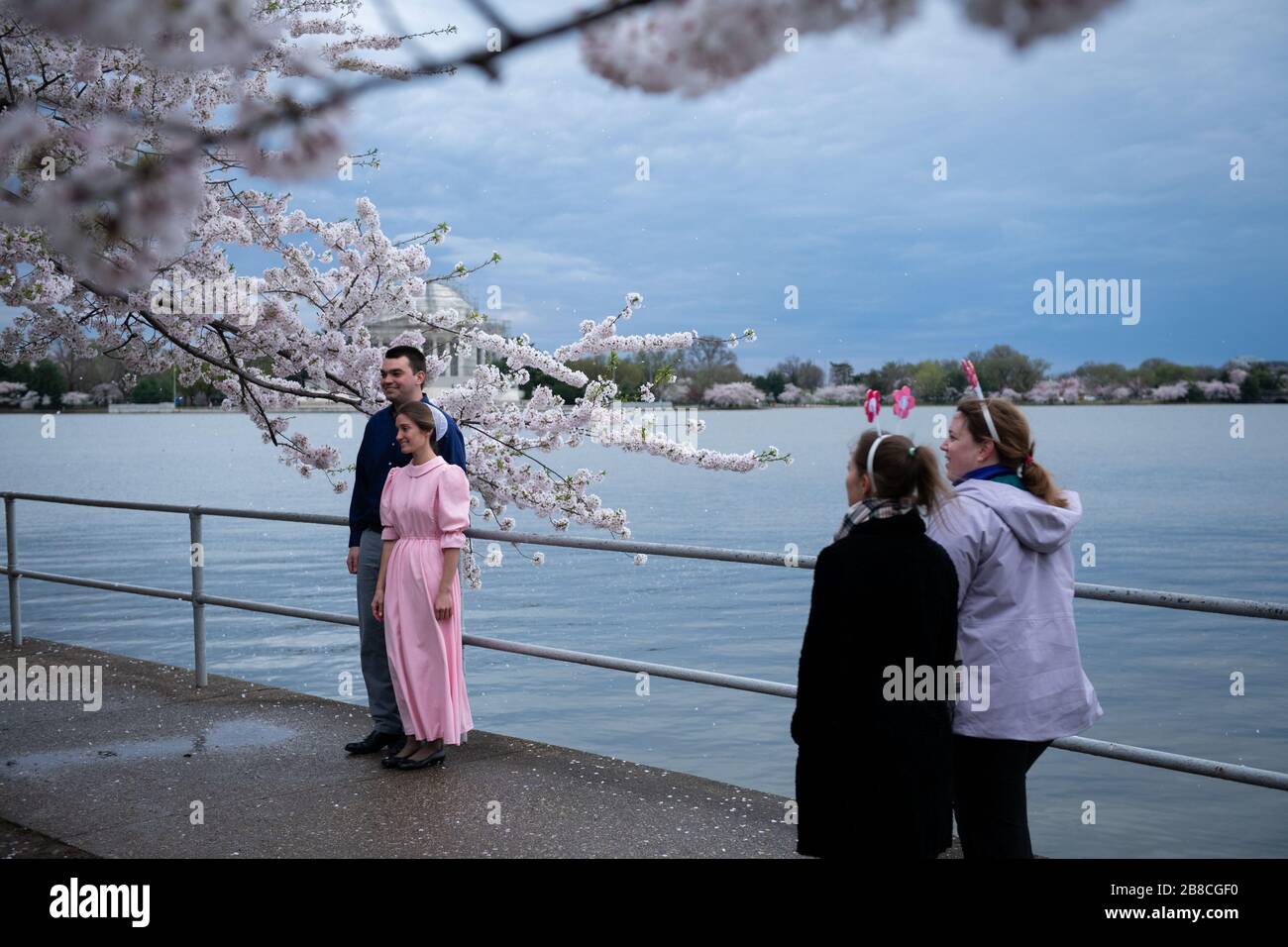 Washington, Stati Uniti. 21 Mar 2020. I visitatori posano per una foto con fiori di ciliegi al picco della fioritura tra la pandemia di coronavirus a Washington, DC, la mattina del 21 marzo 2020. Un gran numero di visitatori è sceso al bacino del Tidal per vedere il picco fiorire nonostante gli avvertimenti sulla salute pubblica di non partecipare, mentre il Senato degli Stati Uniti è pronto a raggiungere un accordo su un piano di salvataggio COVID-19 da 1 trilione di dollari, mentre i senatori hanno lavorato durante il fine settimana su un compromesso. (Graeme Sloan/Sipa USA) Credit: Sipa USA/Alamy Live News Foto Stock