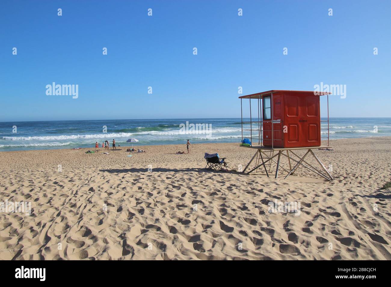Spiaggia sabbiosa e oceano Pacifico a Wilderness, Sud Africa, oltre alla Garden Route. Persone sulla spiaggia. Una capanna di baywatch in primo piano. Africa. Foto Stock