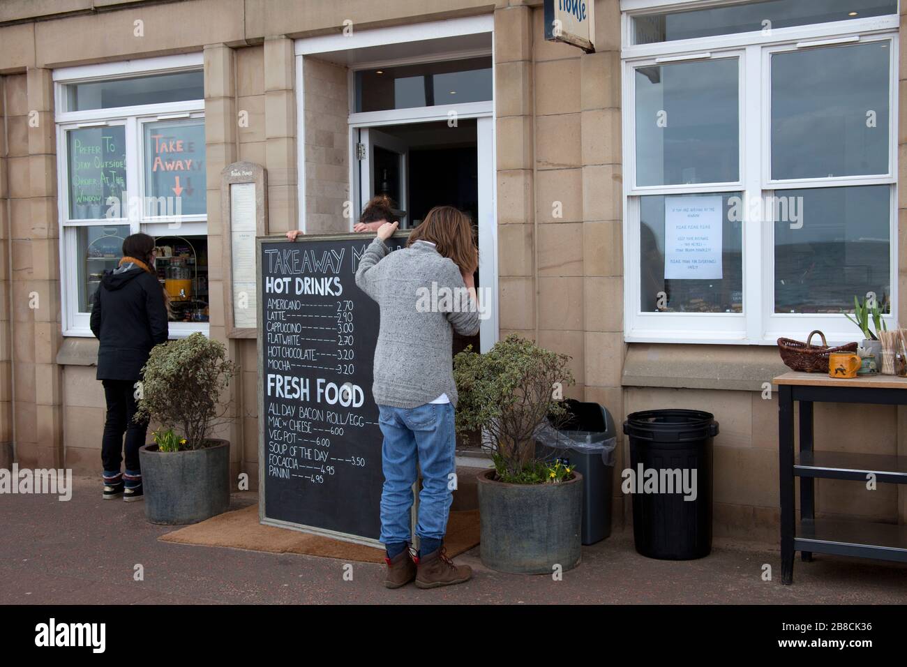 Portobello, Edimburgo, Scozia, Regno Unito. 21st Mar, 2020. Il tempo è calmo e il pubblico procede come di consueto. La Scozia ha avuto 51 nuovi casi di Coronavirus che porta in totale a 373, un'altra morte durante la notte porta in totale a 7. Pubblico ancora congregate e hanno interazione sociale come normale. Insieme ai pub locali che sono chiusi come consigliato dal governo e il Beach cafe che sta facendo via attraverso un servizio di finestre, solo due giovani che indossano visibilmente le maschere sembrano prendere sul serio la minaccia del virus. Foto Stock