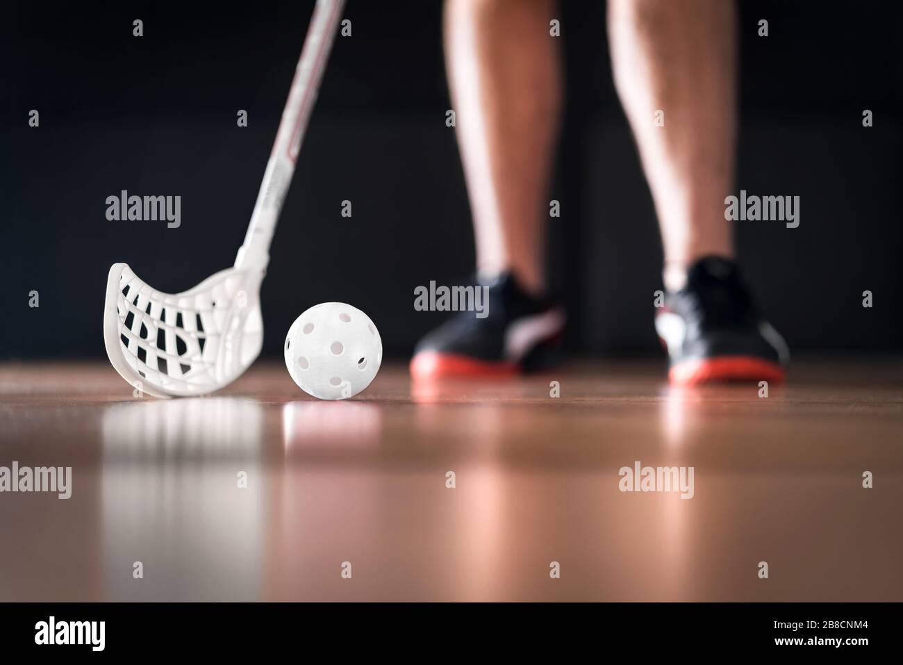 Giocatore di Floorball in piedi con palla bianca e bastone. Concetto di hockey del pavimento. Foto Stock