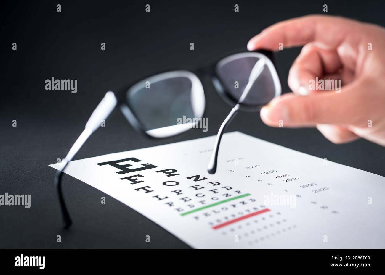 Occhiali optician. Grafico di prova della vista sullo sfondo. Oculari che fissano e riparano occhiali o lenti. Optometrista o oftalmologo. Foto Stock