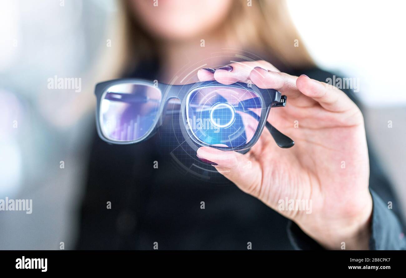 Occhiali intelligenti con schermo virtuale con interfaccia futuristica high tech. Donna che tiene occhiali con interfaccia nanotech. Visione della realtà aumentata. Foto Stock