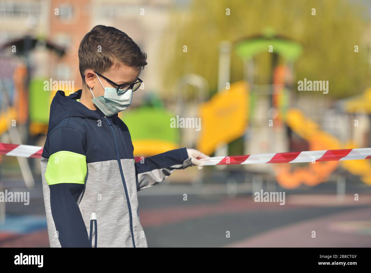 Deluso ragazzo solitario indossare maschera per la protezione del virus corona diffusione su un parco chiuso vuoto Foto Stock