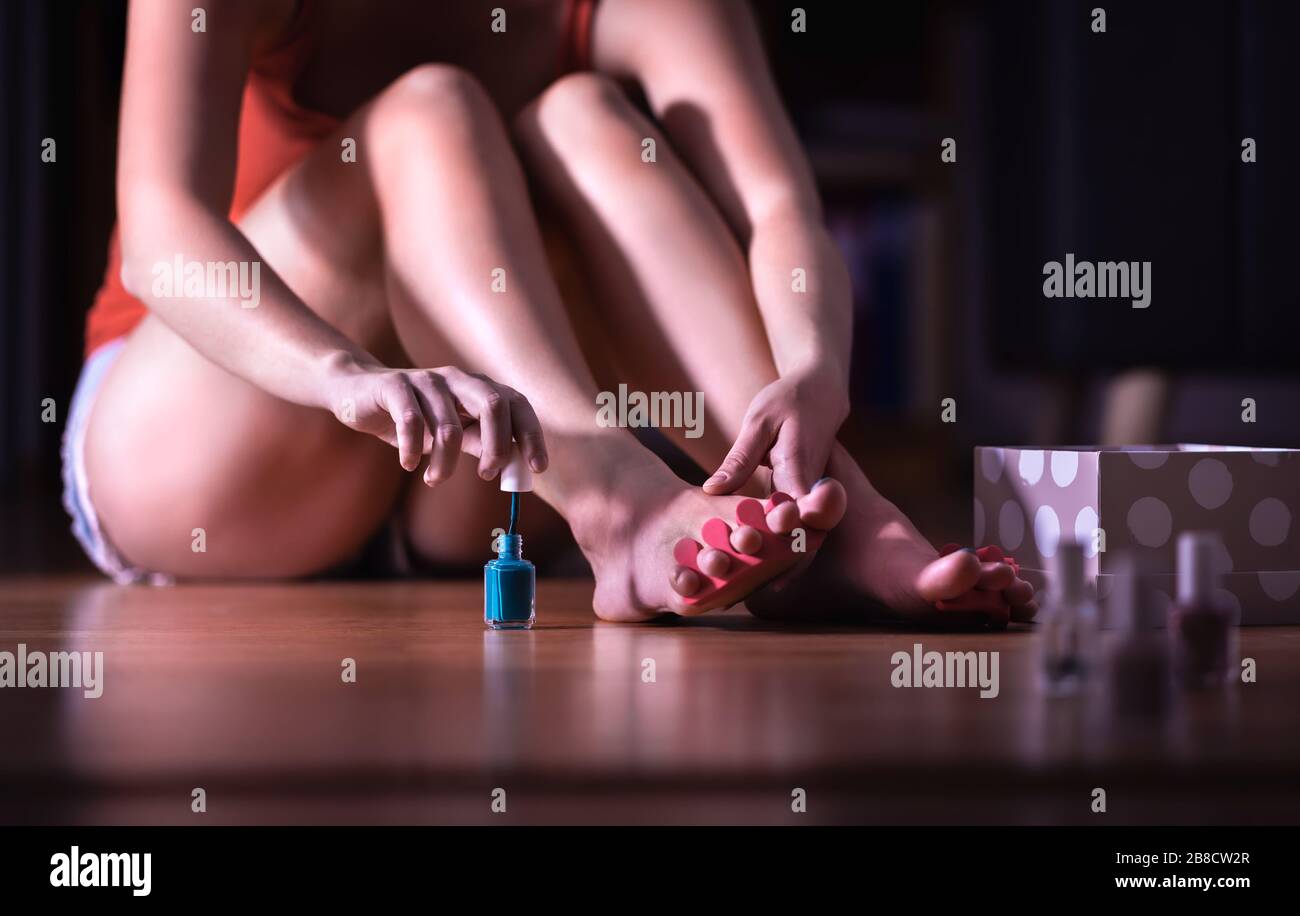 Pedicure a casa. Giovane donna che dipinge i chiodi della punta con smalto del chiodo. Ragazza che usa il pennello per applicare la vernice ai toenails. Foto Stock