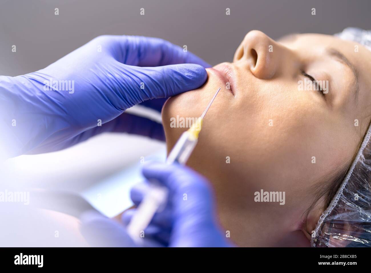 Iniezione del labbro, aumento e miglioramento nella clinica di chirurgia plastica con ago e siringa. Donna che ha un trattamento cosmetico. Foto Stock