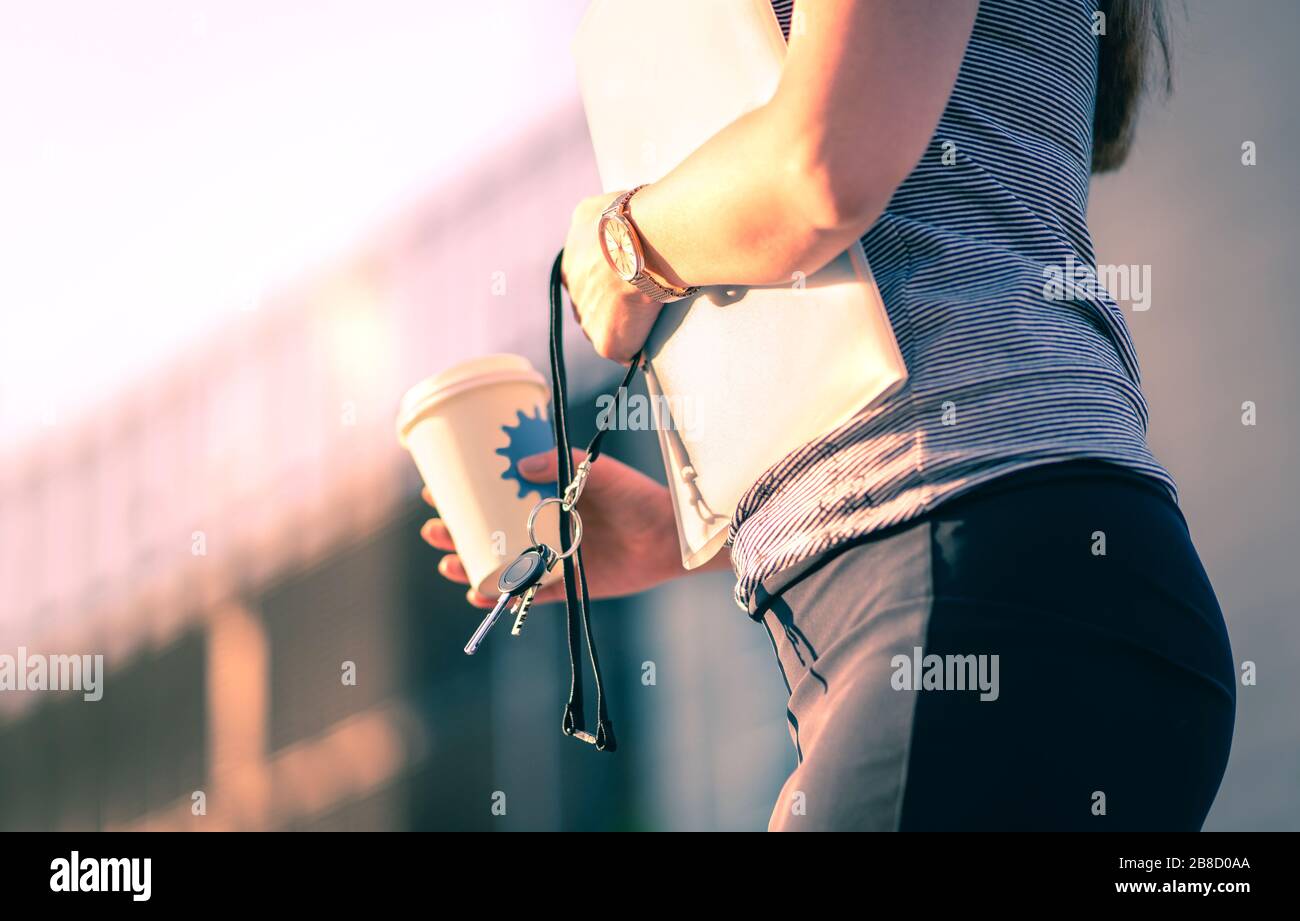 Andare al lavoro la mattina. Donna d'affari che tiene le chiavi e la tazza di caffè mentre cammina all'ufficio nella città urbana. Realtor femminile sicuro. Foto Stock