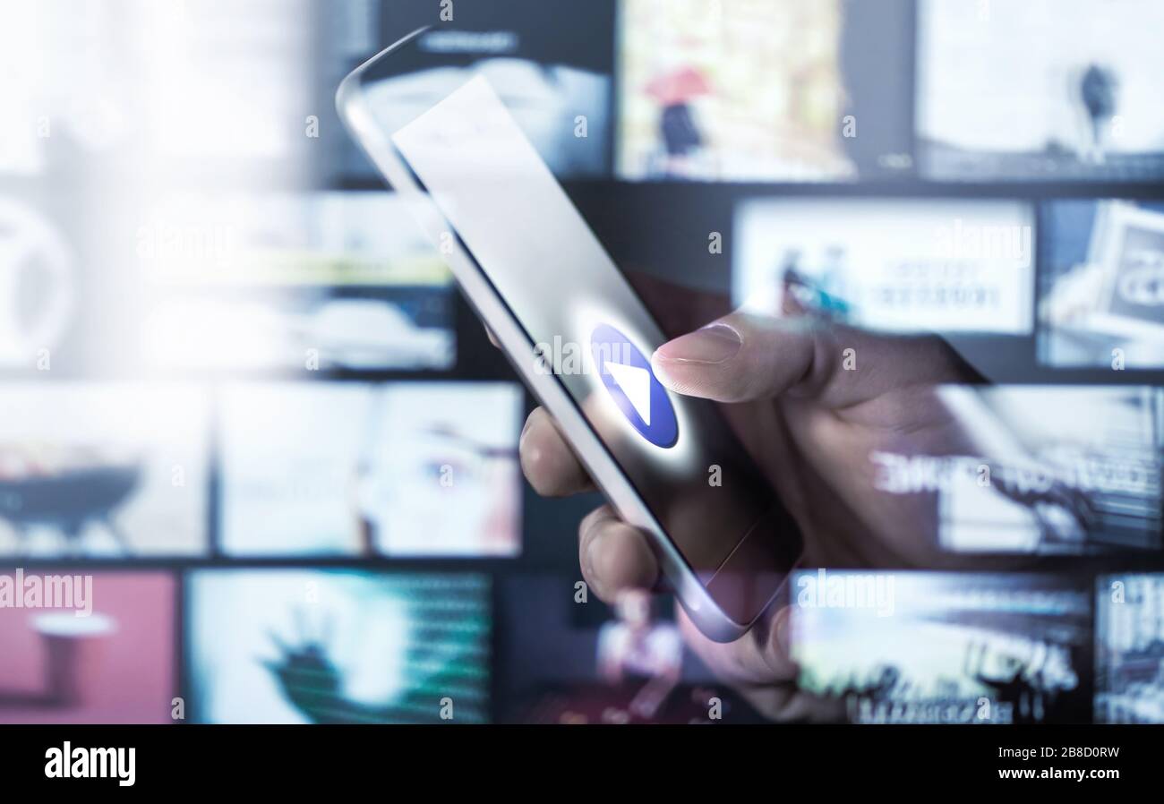 Guardare film e serie con lo smartphone. Servizio on demand (VOD). Tecnologia multimediale futura nel telefono cellulare. Uomo che preme il tasto Play. Foto Stock