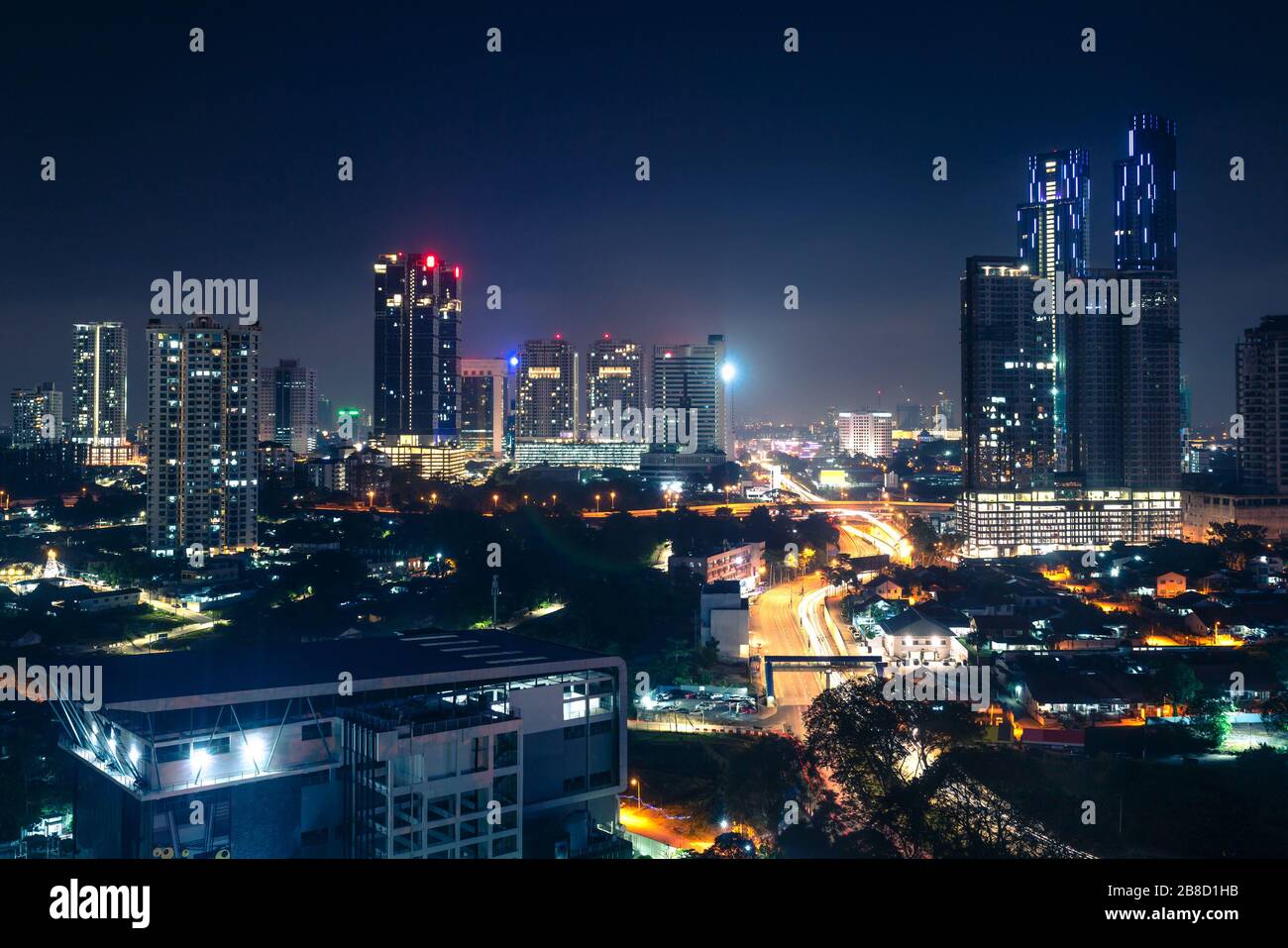 Johor Bahru, Malesia, di notte. Città malese con traffico su autostrada e moderni edifici d'affari e hotel in centro. Skyline urbano panoramico. Foto Stock