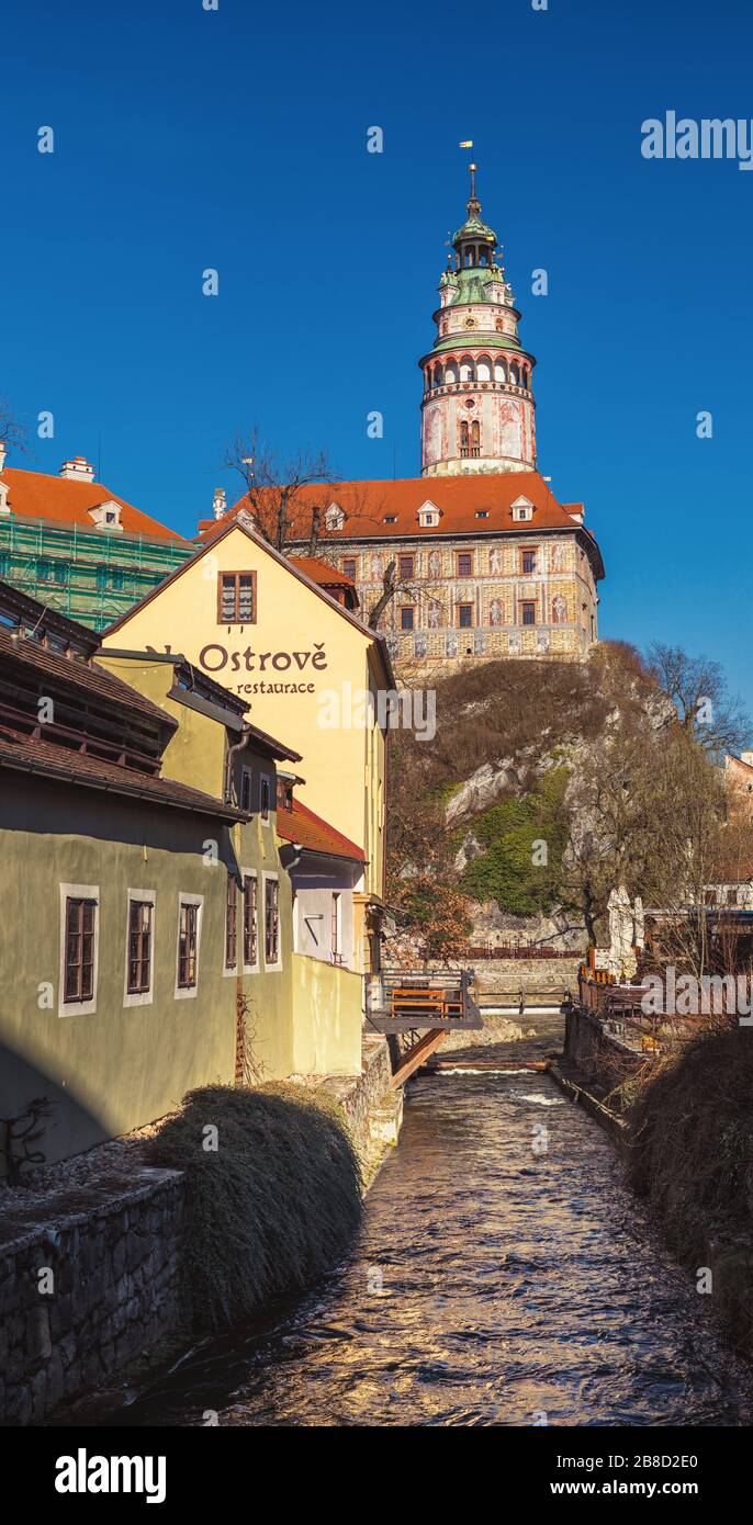Canale d'acqua tra gli edifici della città vecchia, castello torre sullo sfondo, Cesky Krumlov Foto Stock