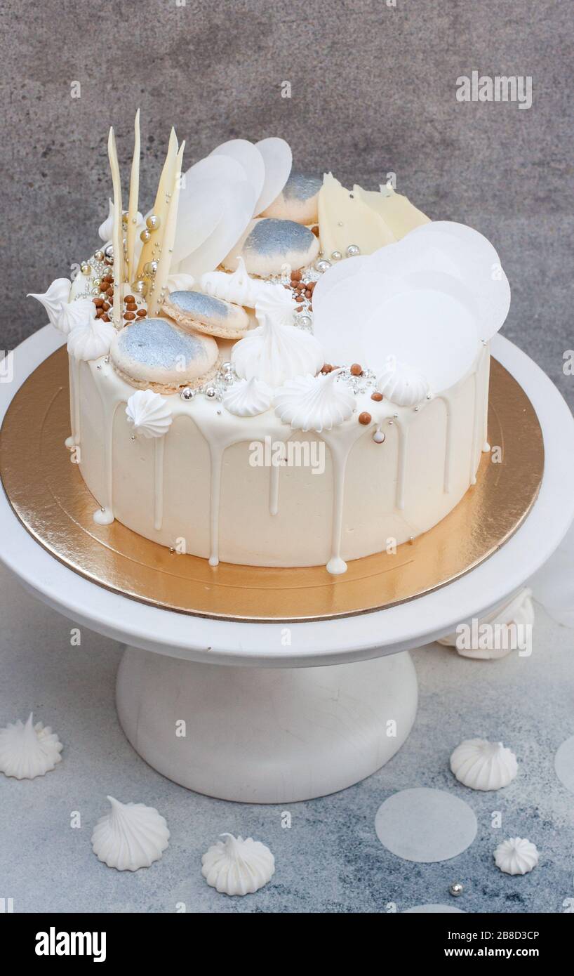 Elegante torta nuziale bianca con decorazione al cioccolato, meringhe e  macaroon su sfondo grigio Foto stock - Alamy