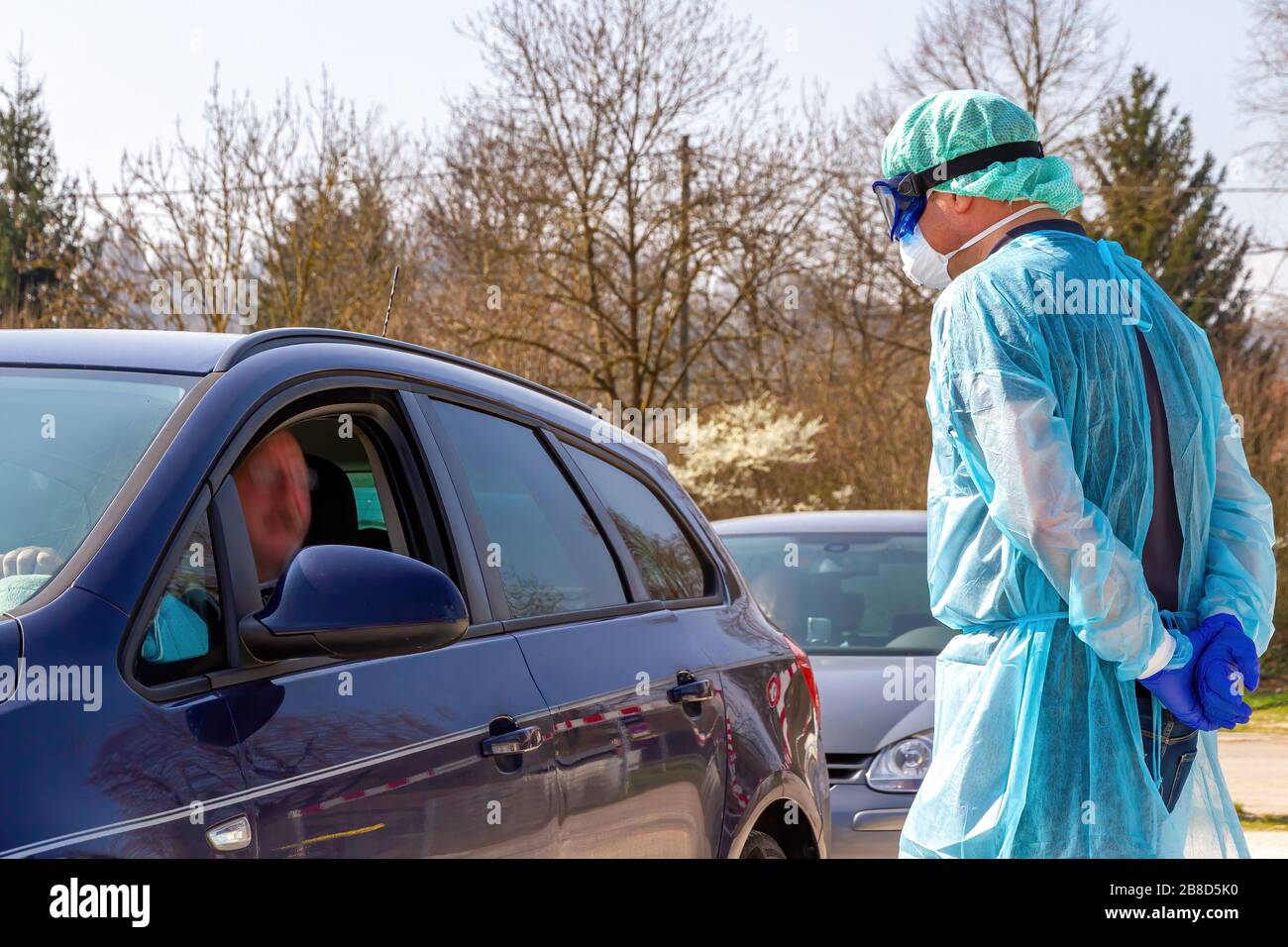 Medico su una stazione di prova del coronavirus che parla con i pazienti nelle loro automobili Foto Stock