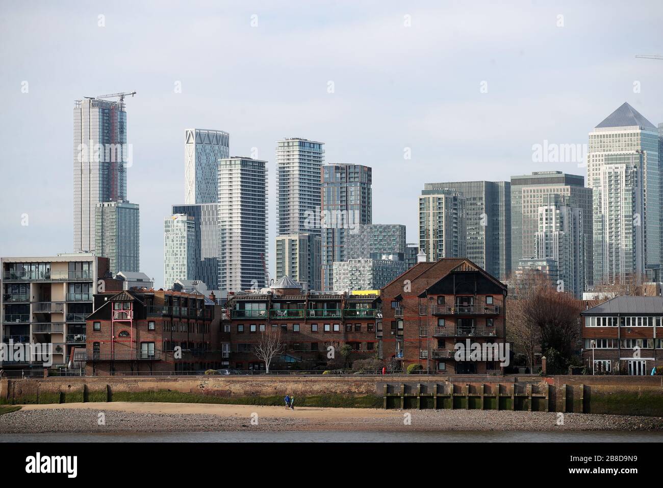 Una vista attraverso il Tamigi del quartiere finanziario a Canary Wharf a Londra dopo che il primo Ministro Boris Johnson ha ordinato pub, caffè, nightclub, bar, ristoranti, teatri, centri per il tempo libero e palestre di vicino a combattere il coronavirus. Foto Stock