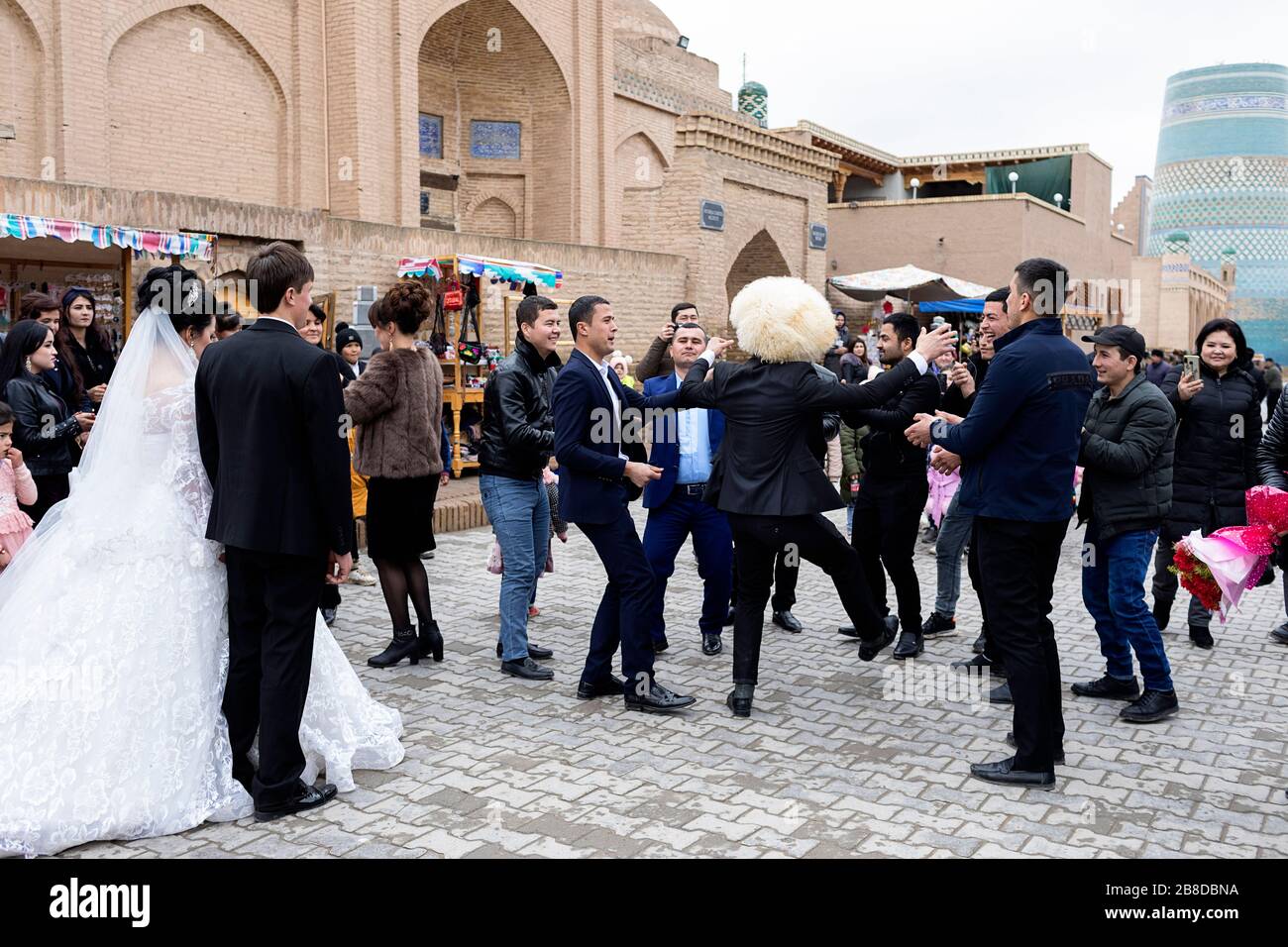 Gli ospiti dei matrimoni in ballo la strada durante una festa di nozze, Khiva, Uzbekistan Foto Stock