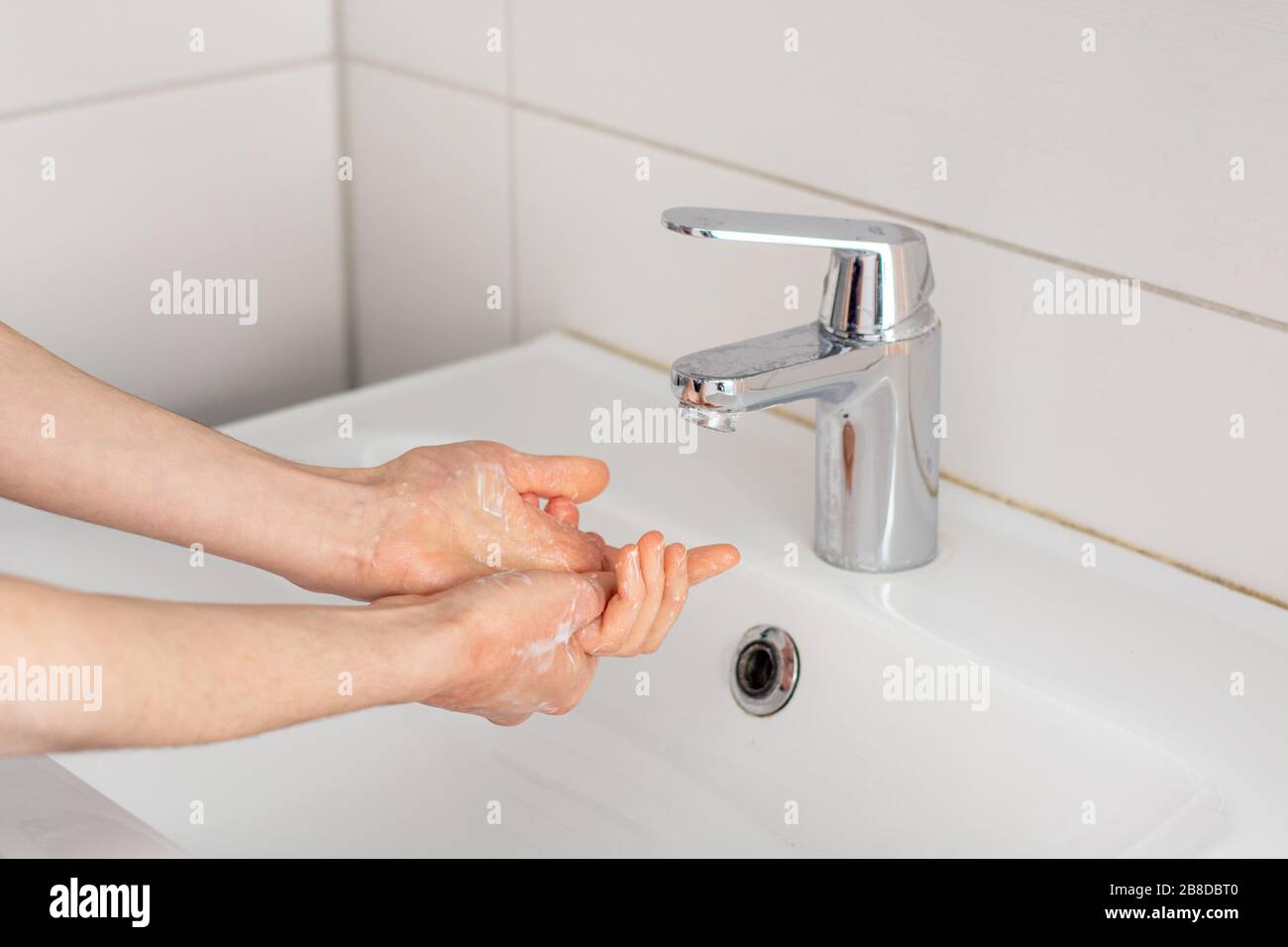 Mettere le mani in bagno prima di lavarsi sotto l'acqua del rubinetto da vicino Foto Stock