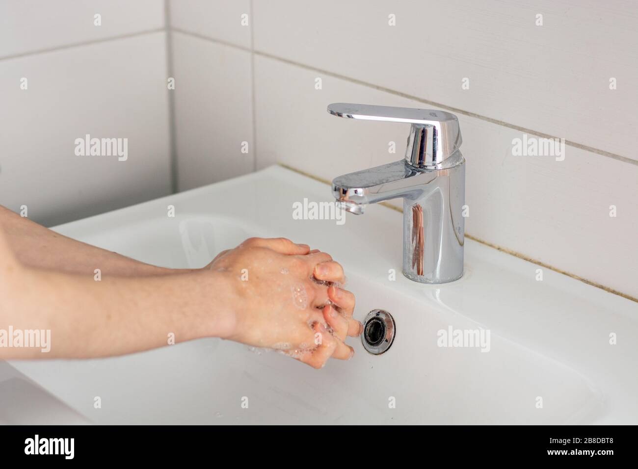 Mettere le mani in bagno prima di lavarsi sotto l'acqua del rubinetto da vicino Foto Stock
