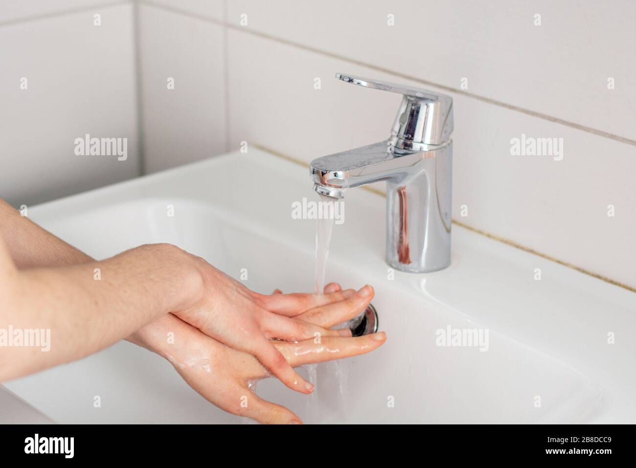 Lavare le mani con sapone sotto l'acqua del rubinetto da vicino Foto Stock