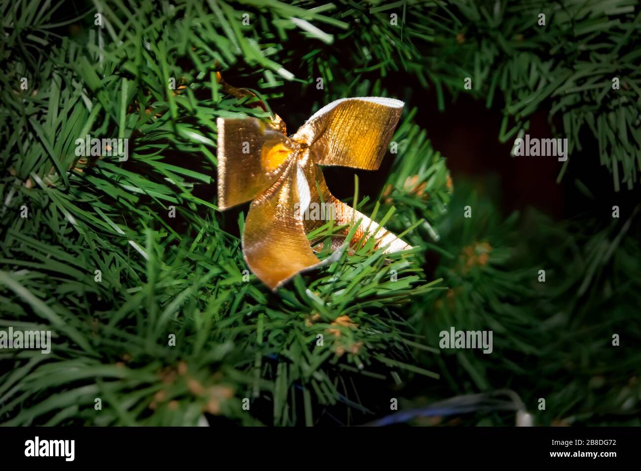 L'arco d'oro del nastro tessile è legato al nuovo anno o all'abete rosso di Natale. Idee di decorazione dell'albero di Natale per la festa. Interni. I doni mistici ravvivano il miracolo. Foto Stock